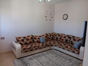 a living room with a couch and a clock on the wall at Alvi apartment in Shkodër