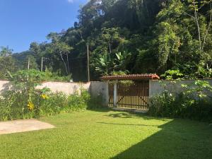 ein Tor in einem Garten mit einem Zaun in der Unterkunft Casa Ampla e Confortável a 10 minutos Praia Ubatumirim Cambuca in Ubatuba