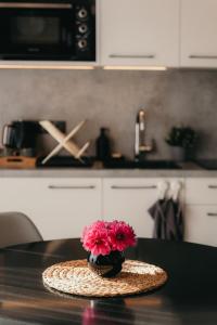 a vase with pink flowers on a table in a kitchen at Villa Lakstīgalas in Skrīveri