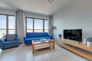 uma sala de estar com um sofá azul e uma televisão em Wave Apartments - SZAFARNIA OLD TOWN em Gdansk