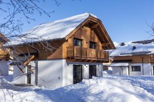 a wooden house with a balcony in the snow at Chalet Speiereck 2 in Mariapfarr