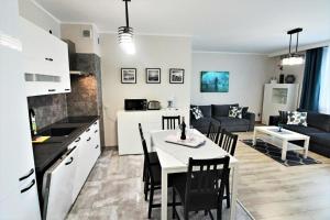 cocina y sala de estar con mesa y sillas. en Bliżej Morza Deluxe Apartmenty, en Kołobrzeg