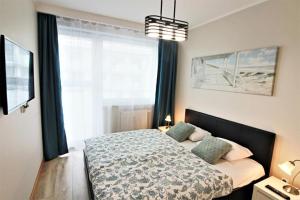 1 dormitorio con cama y ventana grande en Bliżej Morza Deluxe Apartmenty, en Kołobrzeg