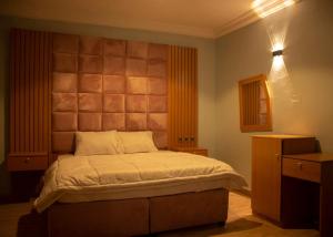1 dormitorio con 1 cama con cabecero grande en Home to Home luxury apartments and suites en Benin City