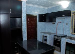 cocina con armarios negros y encimera negra en Home to Home luxury apartments and suites en Benin City
