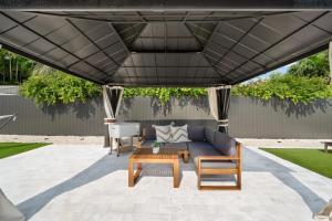 a patio with a couch and a table under a black umbrella at The lux paradise in Tamiami