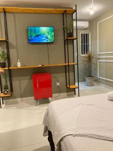 um quarto com uma cama e uma televisão na parede em Jr FLATS em João Pessoa