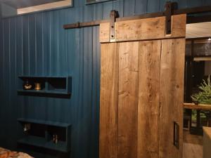 een houten deur in een blauwe muur met planken bij Tiny House in de Boomgaard in Stad aan ʼt Haringvliet