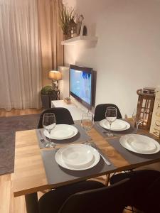 uma mesa de madeira com pratos e copos de vinho em Apartament Stella Park em Stargard