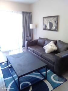 een woonkamer met een bruine bank en een tafel bij Waterfall Ridge Apartments - Kick back and Relax in Midrand