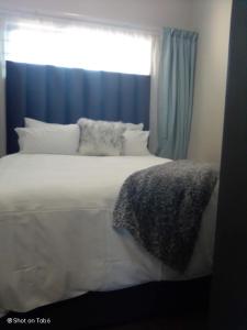 een slaapkamer met een wit bed en een raam bij Waterfall Ridge Apartments - Kick back and Relax in Midrand