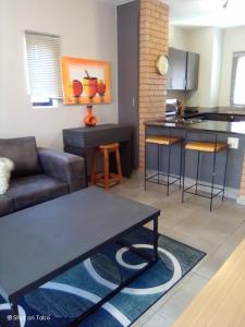 een woonkamer met een bank en een keuken bij Waterfall Ridge Apartments - Kick back and Relax in Midrand