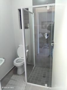 La salle de bains est pourvue de toilettes et d'une douche en verre. dans l'établissement Waterfall Ridge Apartments - Kick back and Relax, à Midrand