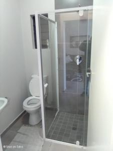 a bathroom with a toilet and a glass shower at Waterfall Ridge Apartments - Kick back and Relax in Midrand
