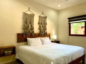 um quarto com uma cama com lençóis brancos e lustres em La Selva Apartments Tulum em Tulum
