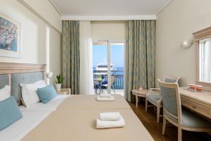 ein Hotelzimmer mit einem Bett, einem Schreibtisch und einem Fenster in der Unterkunft Hotel Timoleon in Limenas