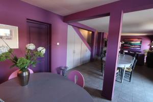 a purple room with a table with a vase of flowers on it at Domaine de Godchure - Gîte & Spa 