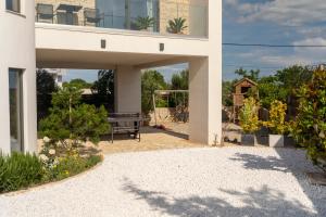 ein weißes Haus mit einer Terrasse mit einer Bank in der Unterkunft Villa Elani - Stylish And Modern 6B Seaview Villa in Vrsi