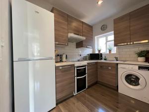 a kitchen with a refrigerator and a washer and dryer at Central Welling Flat in Welling