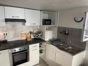eine Küche mit weißen Schränken und einem Waschbecken in der Unterkunft Duplex confortable proche Paris in La Courneuve