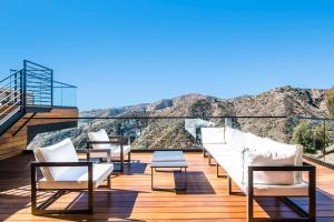 una terraza con sillas blancas y vistas a las montañas. en Linda Flora Modern Estate en Los Ángeles