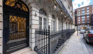 a building with a wrought iron fence next to a street at Shepherd Street, Mayfair in London