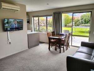a living room with a table and a tv on a wall at Hanmer Apartments in Hanmer Springs