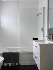 La salle de bains blanche est pourvue d'une douche et d'un lavabo. dans l'établissement Under Walnut Tree, à Rotorua