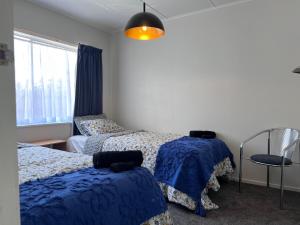 - une chambre avec 2 lits avec des draps bleus et une fenêtre dans l'établissement Under Walnut Tree, à Rotorua