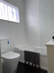La salle de bains blanche est pourvue d'une baignoire et de toilettes. dans l'établissement Under Walnut Tree, à Rotorua