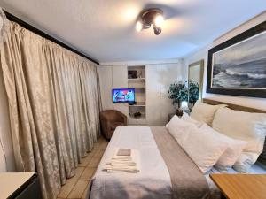 a small bedroom with a bed and a television at Douglasdale 3 Queen Double Beds Loft - 2nd Bedroom own entrance kitchenette & bathroom- Parking - Serviced - Wood & Gas Braais - Pool & Lapa - Ultra Hi Speed WiFi with DSTV & Movie Streaming - Full office backup - in room iMac & iPad - Printer & Copier in Sandton