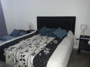 1 cama con manta blanca y negra y almohadas azules en ENCANTO SERRANO en Villa Carlos Paz