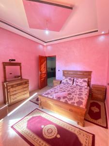 1 dormitorio con pared de color rosa, cama y espejo en Sun house 1, en Imsouane