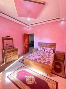 una camera da letto con pareti rosa, letto e specchio di Sun house 1 a Imsouane