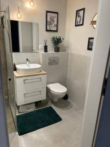 a white bathroom with a sink and a toilet at Apartament Calineczka in Reda