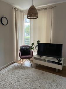 a living room with a television and a chair at Apartament Calineczka in Reda