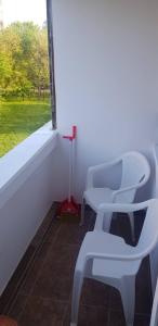 - deux chaises blanches assises dans une pièce avec fenêtre dans l'établissement Apartman Stefan, à Pančevo