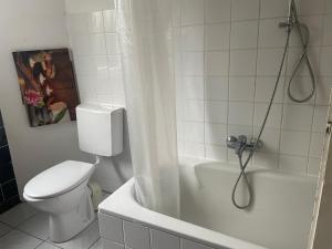 uma casa de banho branca com um WC e um chuveiro em Ferienwohnung in Saarbrücken em Riegelsberg