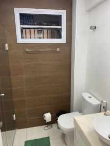 a bathroom with a toilet and a sink and a window at Apto frente Praia Itararé in São Vicente