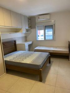 a small room with two beds and a window at Apto frente Praia Itararé in São Vicente +13 photos