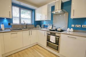 uma grande cozinha com armários brancos e paredes azuis em Luxurious Townhouse In Central Manchester em Manchester
