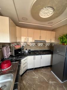 a kitchen with white cabinets and a stainless steel refrigerator at APPART HOTEL OUED EDDAHAB in Khenifra