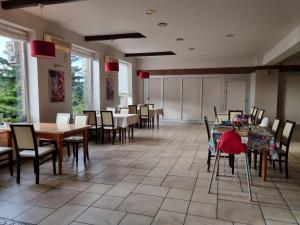 a dining room with tables and chairs and windows at Zajazd Bazylia in Ozorków