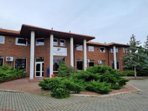 a brick building with trees in front of it at Zajazd Bazylia in Ozorków
