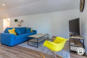 Una sala de estar con un sofá azul y sillas amarillas. en Gîte de la Pépinière, en Argelès-Gazost