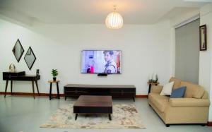 uma sala de estar com um sofá e uma televisão na parede em Brand New Condo Apartment em Kampala