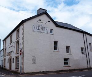 un bâtiment blanc avec un panneau sur son côté dans l'établissement The Cock Hotel, à Bronllys