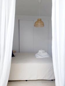 a white bedroom with a bed and a chandelier at SHERRY SUÍTES III apartamentos in Jerez de la Frontera