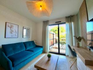 a living room with a blue couch and a large window at Les Loges de la Mer - Pérols in Pérols