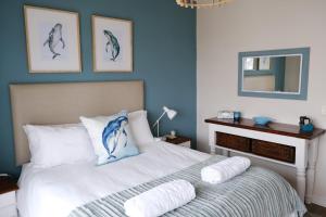 a bedroom with a bed with blue walls and a mirror at Penguin Paradise Apartment Simons Town in Simonʼs Town